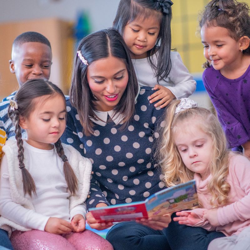 Maestra de cuidado infantil leyendo a niños/as de 3 años