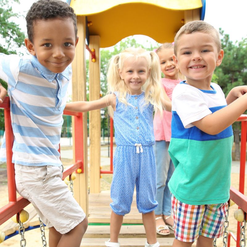 4 Niños sonriendo en el puente del parque infantil