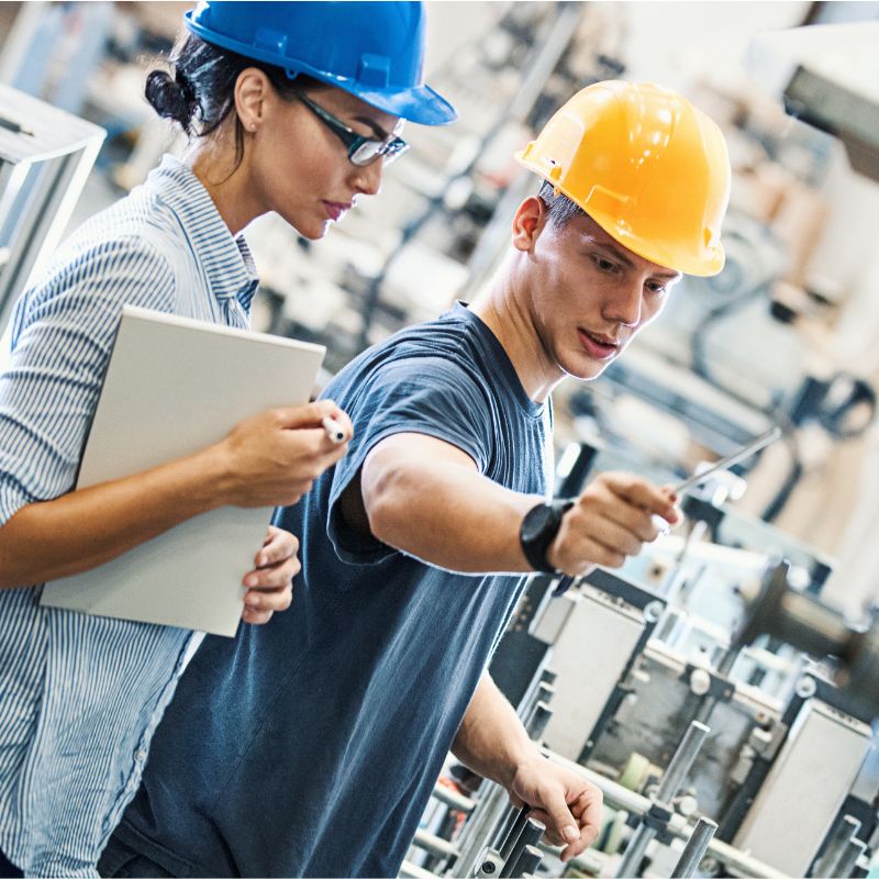 Factory worker holding wearing a blue jumpsuit, holding his yellow hardhat. 